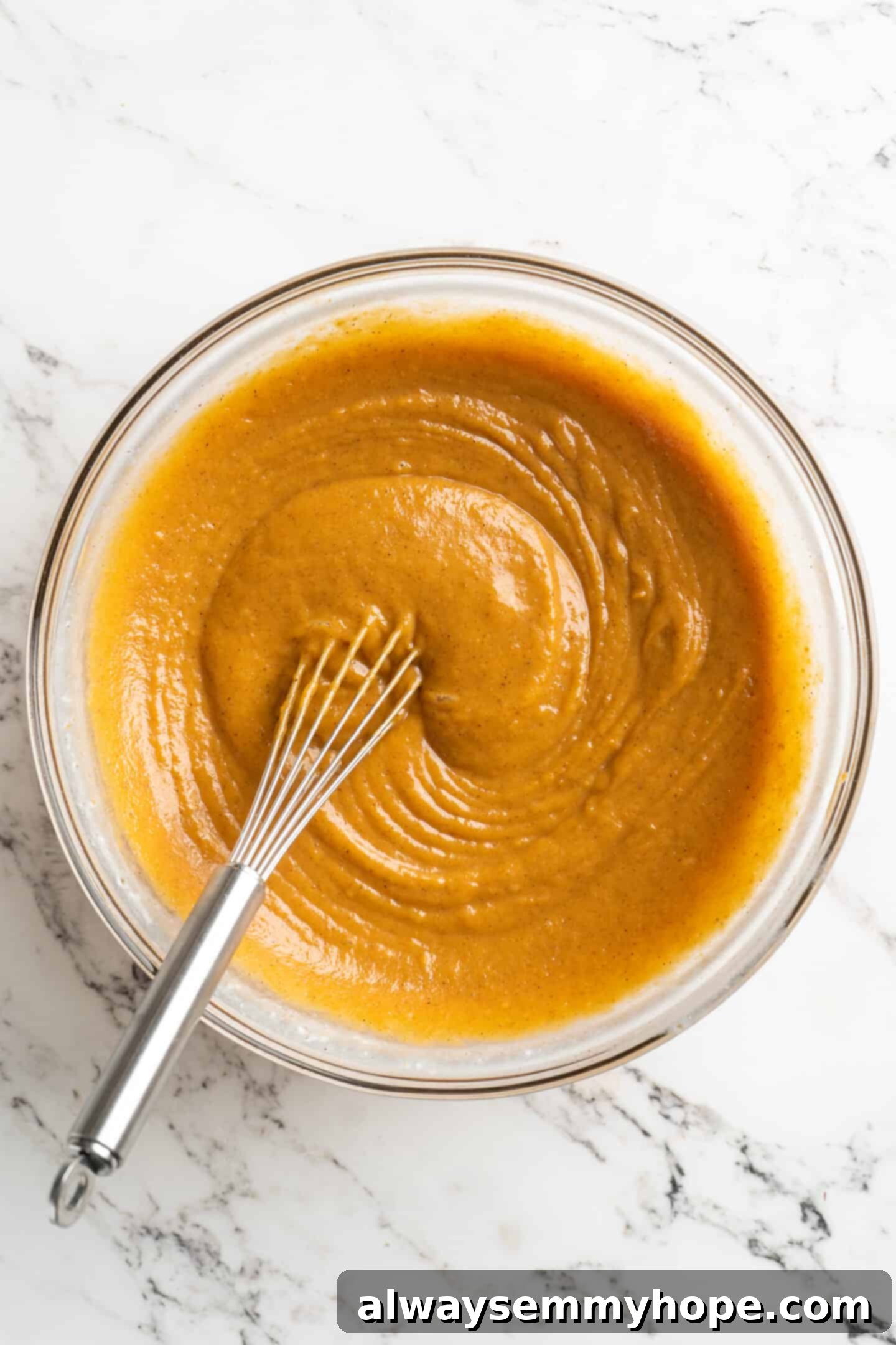 Easy 9-Ingredient Vegan Pumpkin Pie 9 fully mixed in pie base in a glass bowl with whisk in bowl.