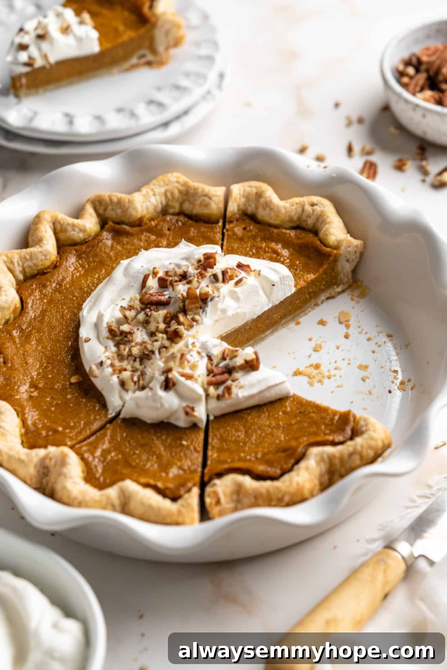This homemade vegan pumpkin pie is perfectly silky, and tastes just like the traditional version! It's the best Thanksgiving dessert! front angled shot of sliced pumpkin pie in a pie dish.