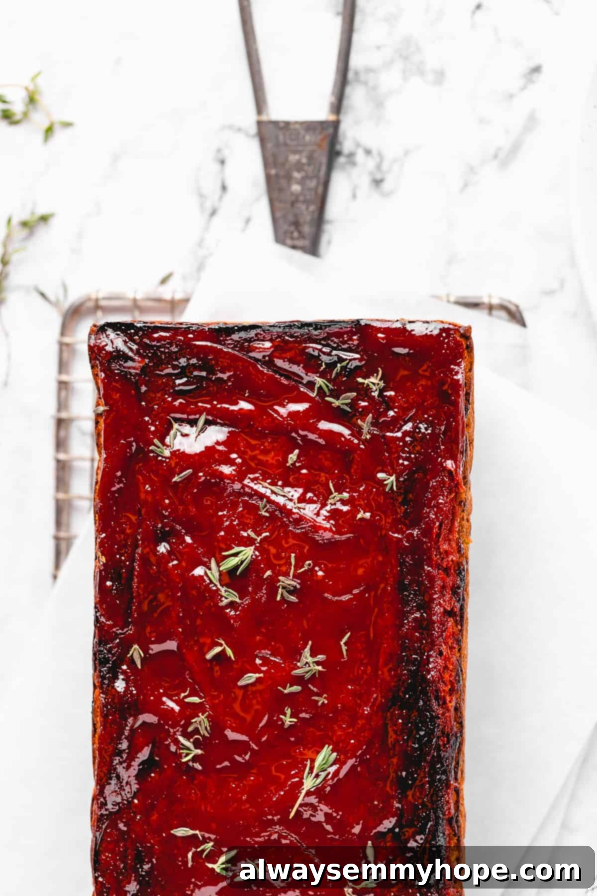 This vegan meatloaf makes a perfect Thanksgiving main dish or entree! It's moist and full of flavor, with just 15 minutes of prep. Dig in! Overhead view of glazed vegan meatloaf on a parchment-lined wire rack.