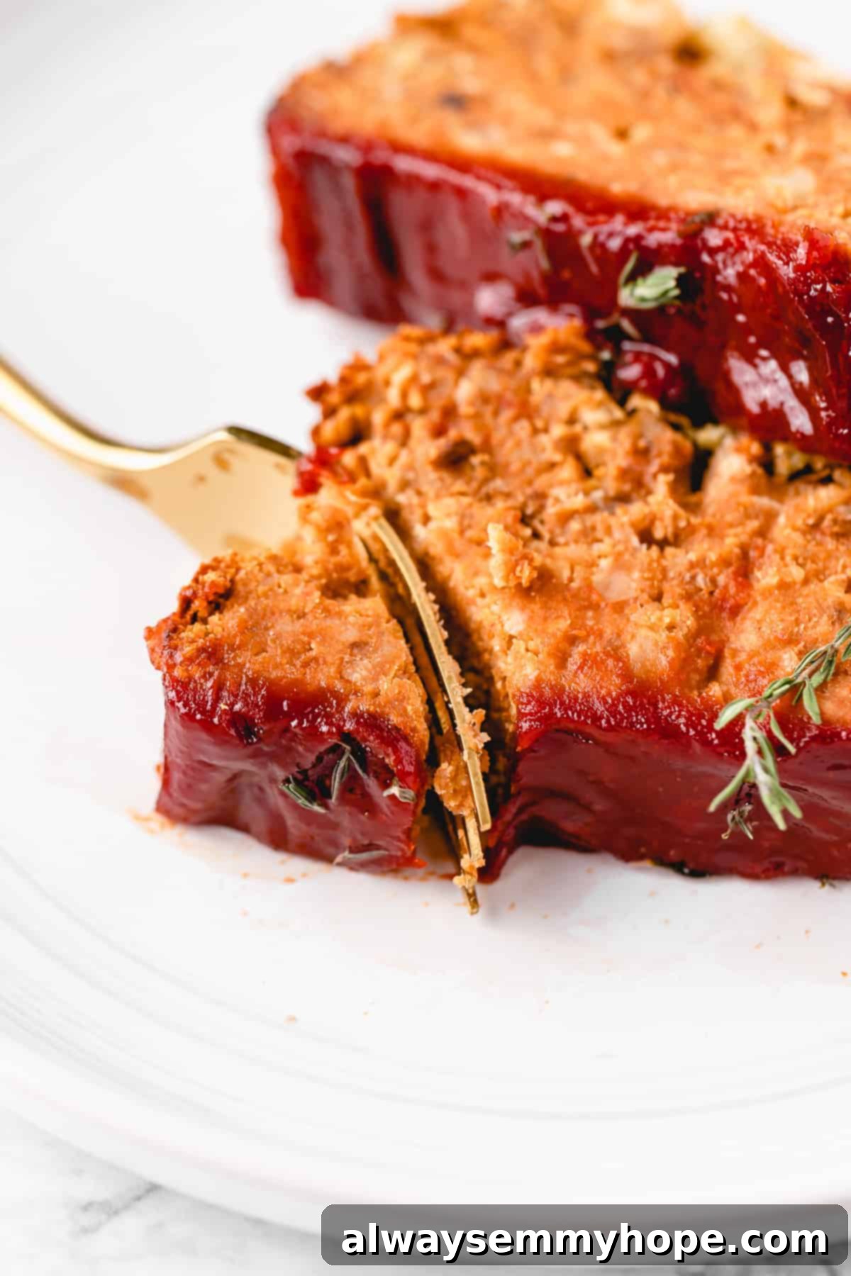 This vegan meatloaf makes a perfect Thanksgiving main dish or entree! It's moist and full of flavor, with just 15 minutes of prep. Dig in! Close up of a fork cutting into the corner of a slice of vegan meatloaf, with a second slice in the background.