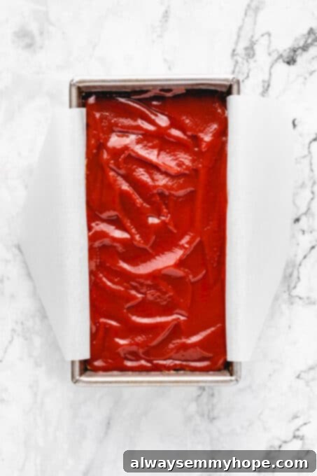 This vegan meatloaf makes a perfect Thanksgiving main dish or entree! It's moist and full of flavor, with just 15 minutes of prep. Dig in! Overhead view of unbaked vegan meatloaf in a parchment-lined loaf pan.