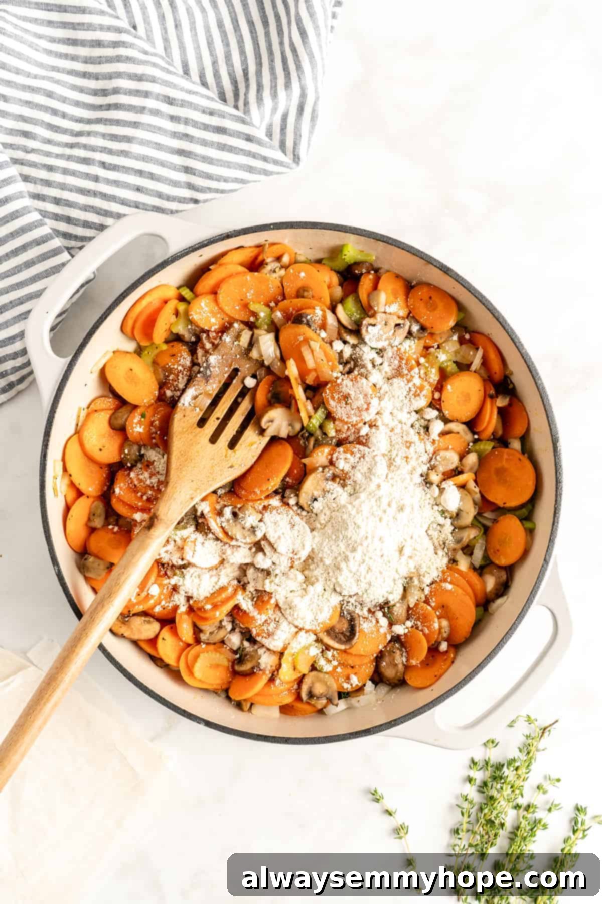 The Best Vegan Pot Pie – Easy, 1-Hour Recipe! Sautéed carrots, mushrooms, and other vegetables in a pot, with flour being sprinkled in to create a roux for the gravy.