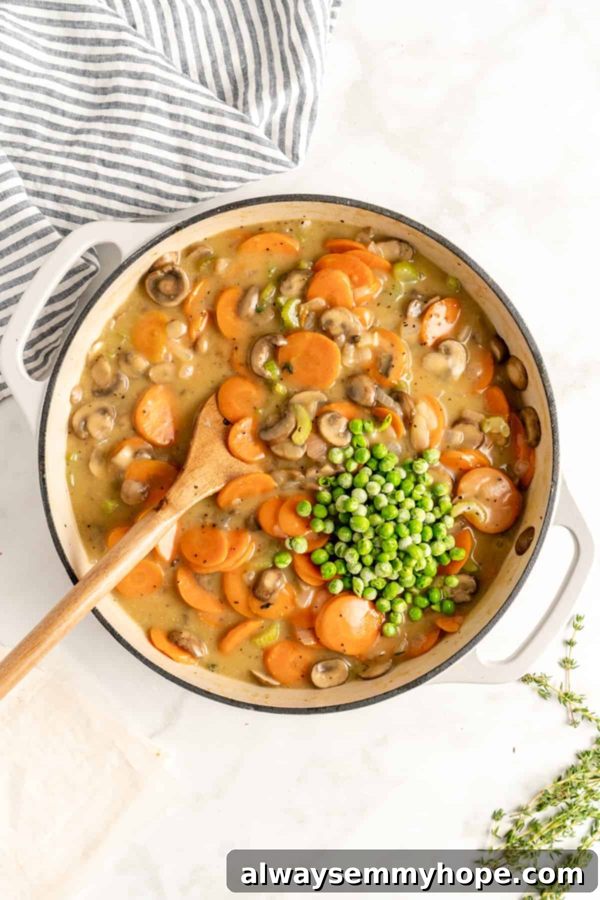 The Best Vegan Pot Pie – Easy, 1-Hour Recipe! Frozen peas being stirred into a rich, creamy pot pie filling in a dutch oven.