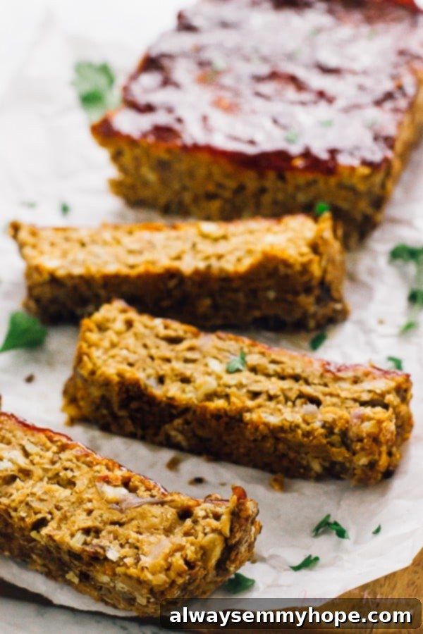 Vegan meatloaf slices on parchment paper with meatloaf in the background. 