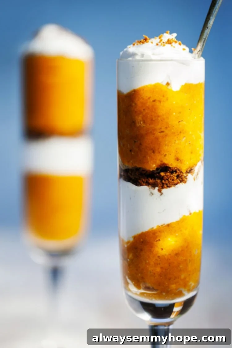 Two tall glasses of pumpkin pie parfait in front of a blue background.