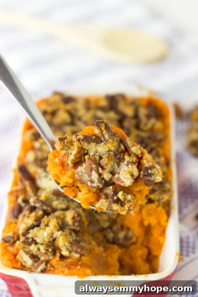 A large spoon holding up a scoop of skinny sweet potato casserole with a baking dish of casserole in the background.