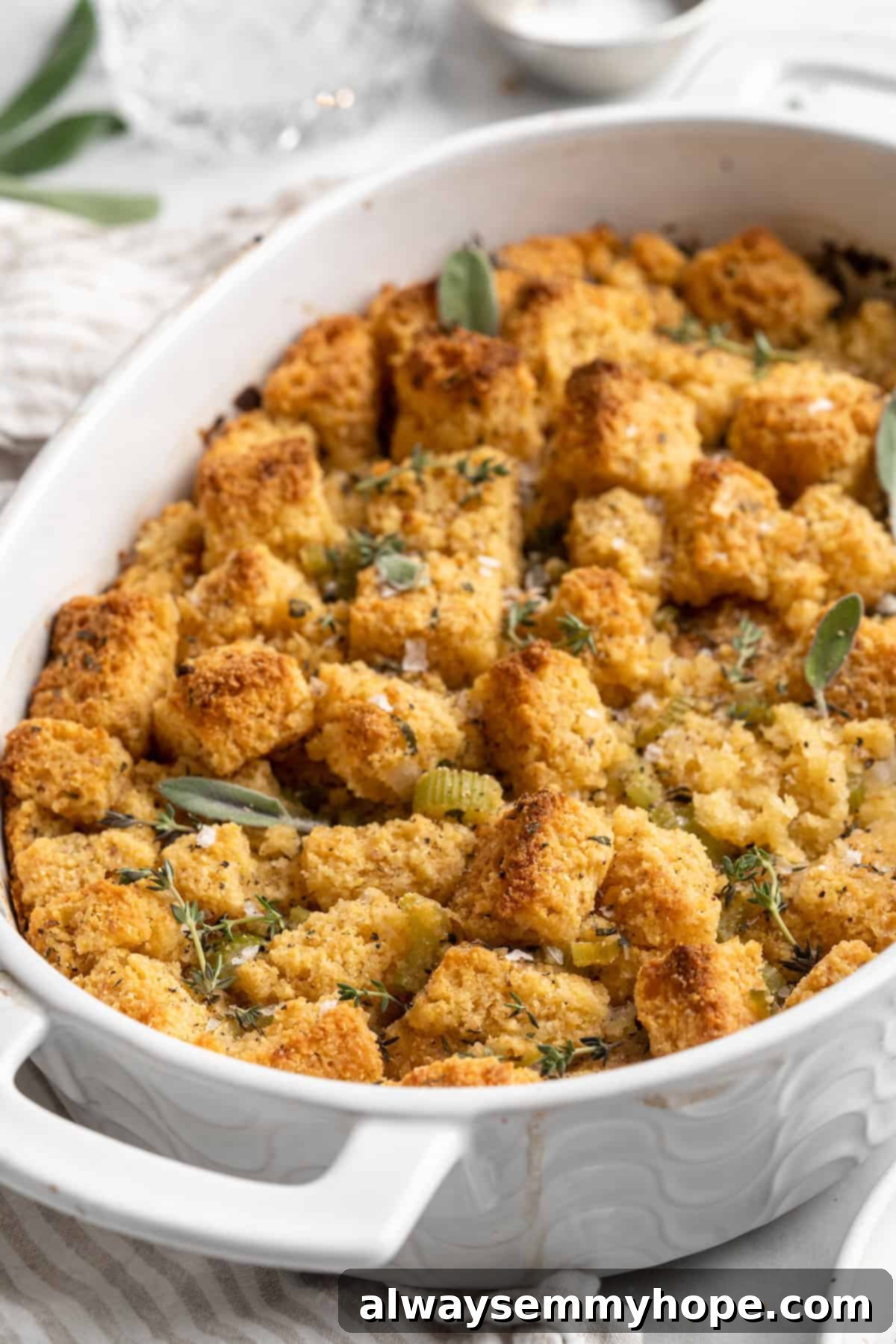 Baking dish of golden-brown cornbread stuffing, garnished with fresh herbs, ready for serving
