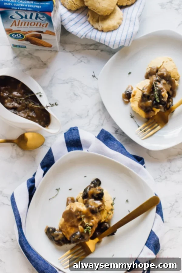 Top down shot of fluffy biscuits generously topped with vegan mushroom gravy, with elegant gold cutlery arranged nearby.