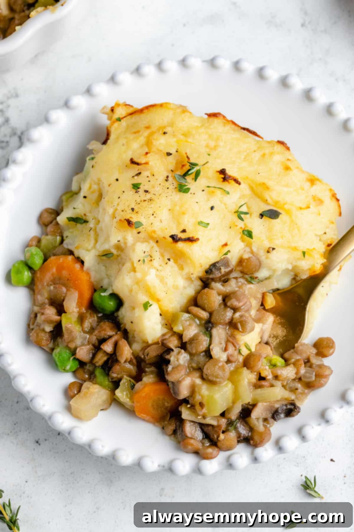 Hearty Vegan Shepherd's Pie 2 Serving of Vegan Shepherd's Pie on white plate with fork, showing crispy mashed potato topping and rich filling