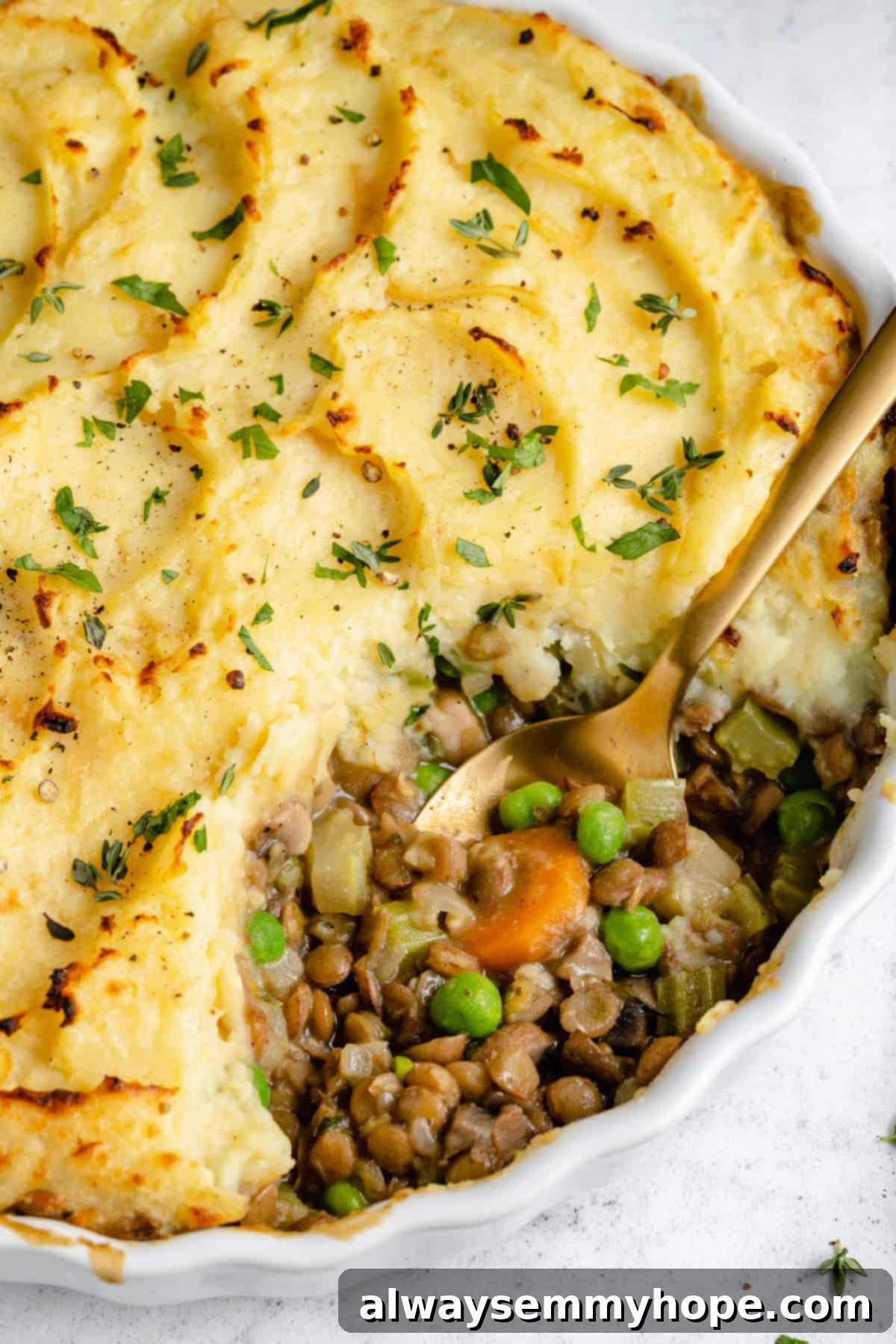 Hearty Vegan Shepherd's Pie 13 Close-up shot of a baked Vegan Shepherd's Pie in a serving dish, with a portion removed to showcase the rich lentil and mushroom filling beneath the golden mashed potato crust