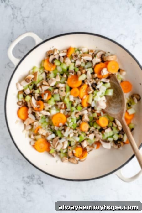Hearty Vegan Shepherd's Pie 4 Overhead shot of raw chopped vegetables (mushrooms, carrots, onion, celery, garlic, thyme) in a Dutch oven before cooking for the Shepherd's Pie filling