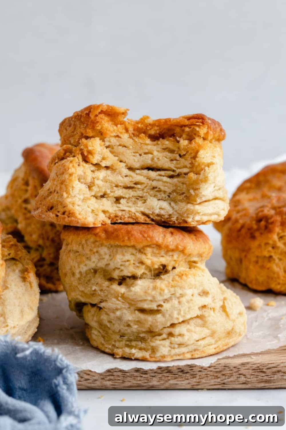 A stack of two perfectly baked, fluffy vegan biscuits on a rustic wooden slab, showcasing their golden crust and tender texture.
