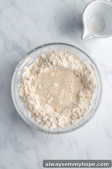 A mound of dry biscuit ingredients in a glass bowl with a well in the center, ready for the cold vegan milk mixture.