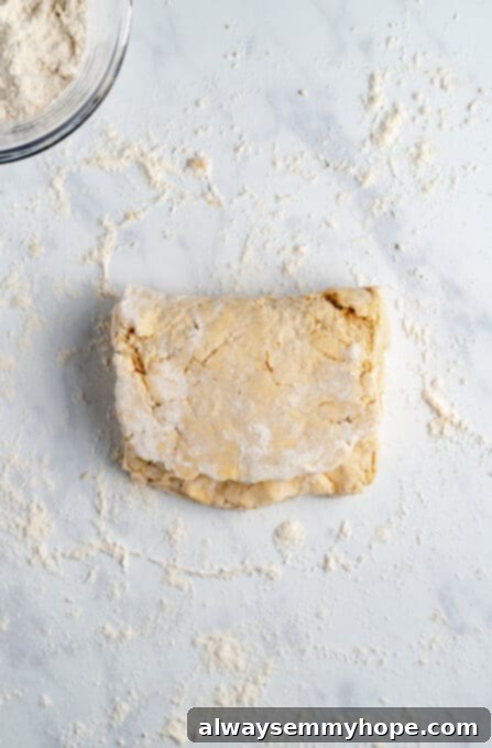 A section of vegan biscuit dough folded over itself on a light granite countertop, demonstrating the layering technique.