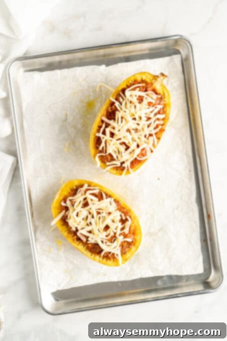 Overhead view of two spaghetti squash boats topped with cheese before baking