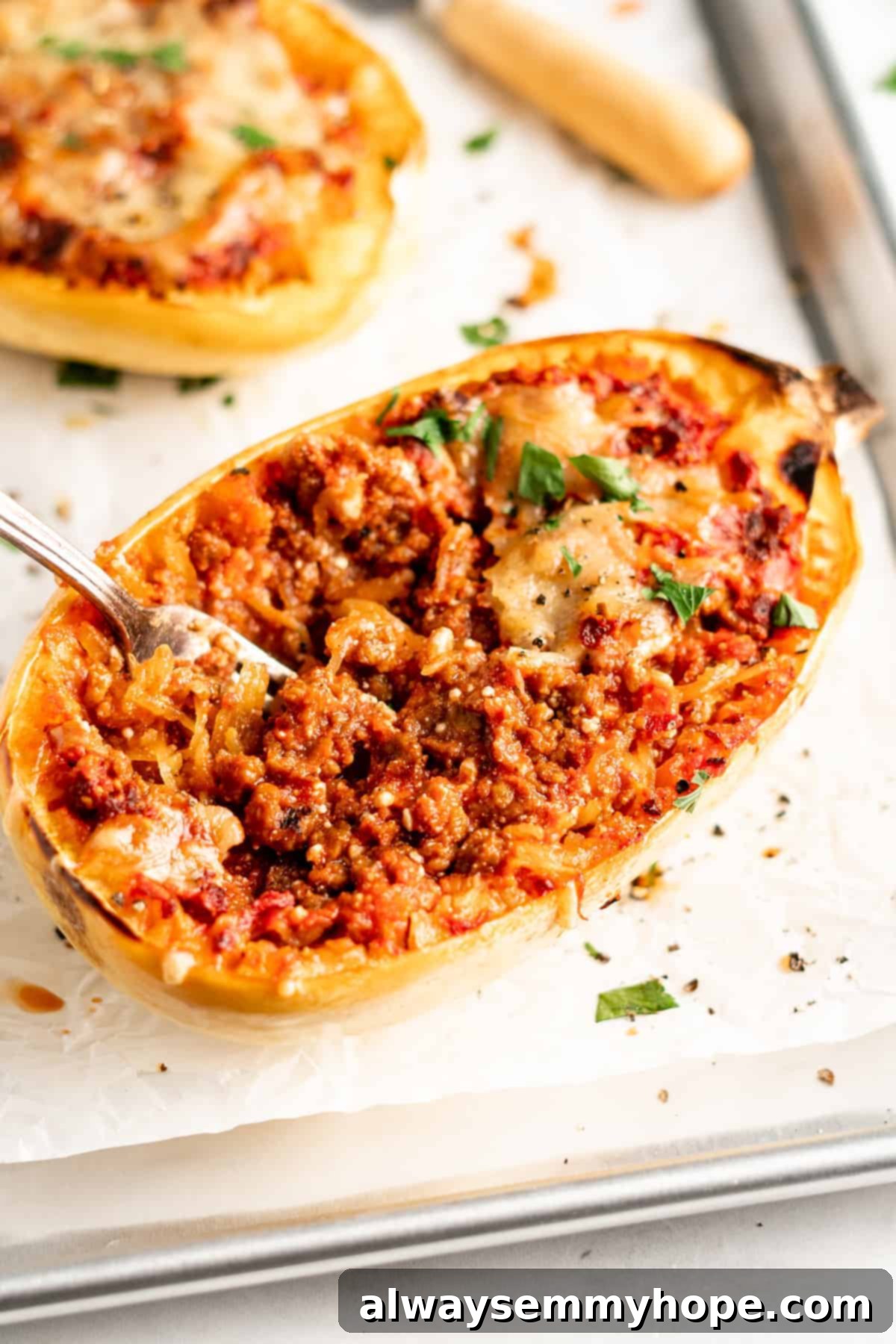 Spaghetti squash lasagna boat on parchment lined baking sheet with fork inside