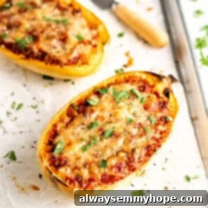 Two lasagna-stuffed spaghetti squash halves on parchment-lined baking sheet