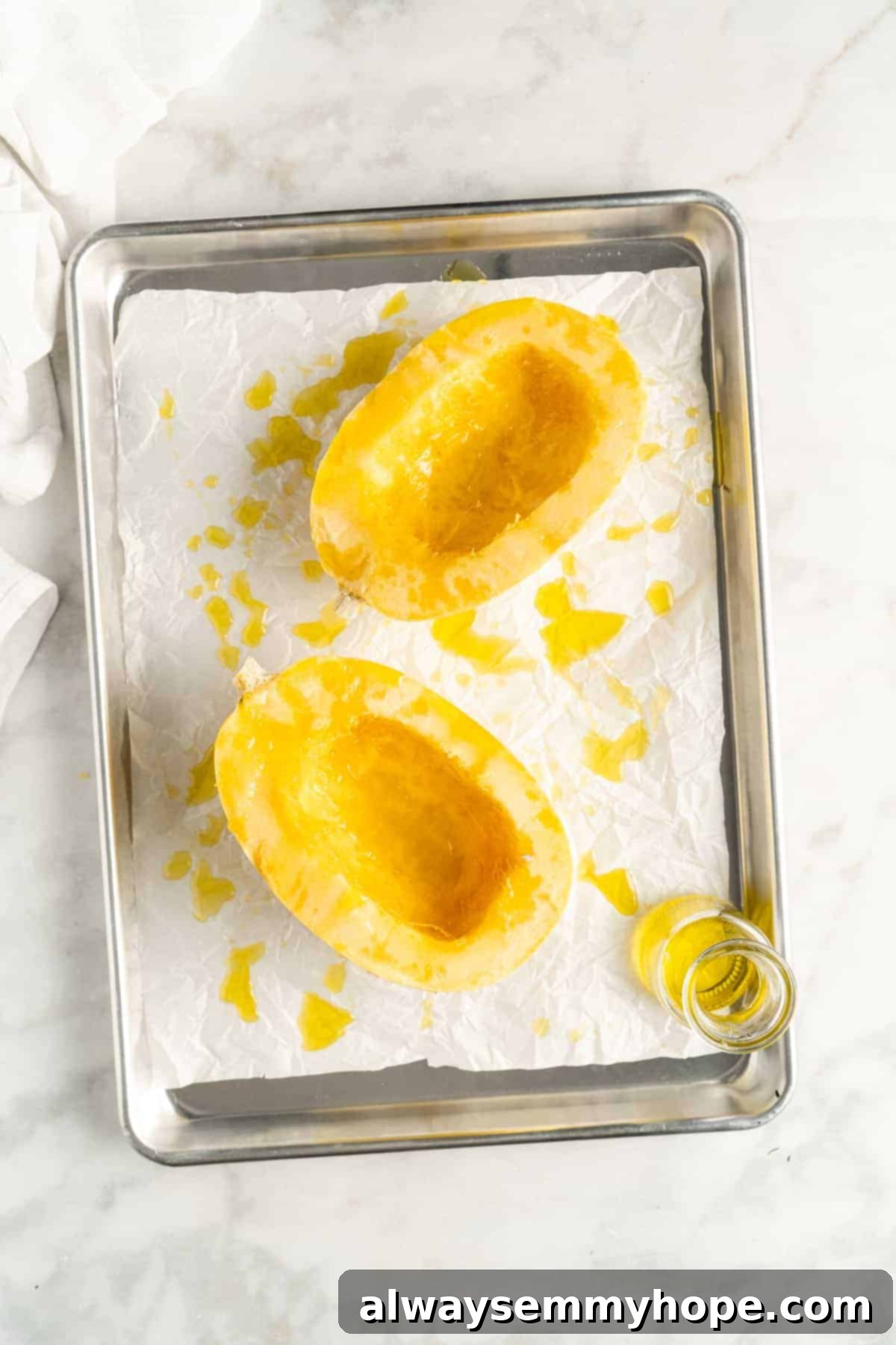 Overhead view of two spaghetti squash halves after drizzling with olive oil