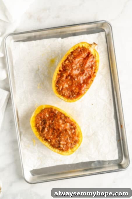 Overhead view of two spaghetti squash halves stuffed with lasagna filling