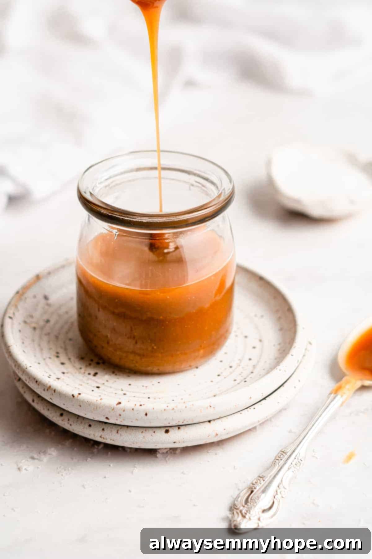 Simple Plant-Based Caramel 11 Warm vegan caramel sauce being drizzled into a glass jar, ready for cooling and storage.