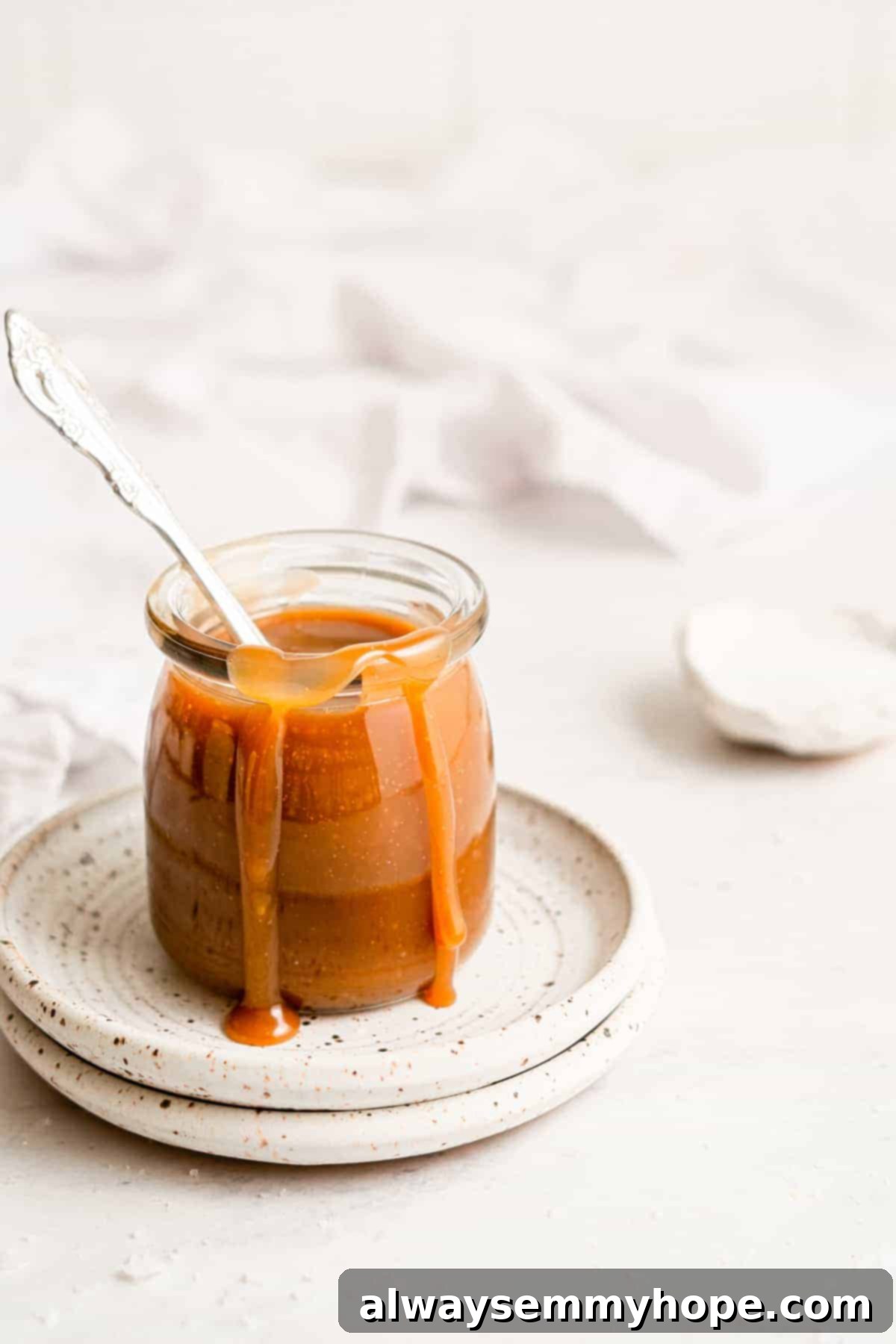 Simple Plant-Based Caramel 10 A jar of vegan caramel sauce with a delightful drip running down the side, emphasizing its rich and luscious texture.