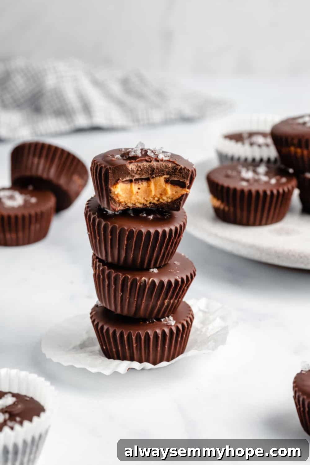 A stack of four vegan peanut butter cups, with a bite taken from the top one, revealing the rich filling and chocolate.
