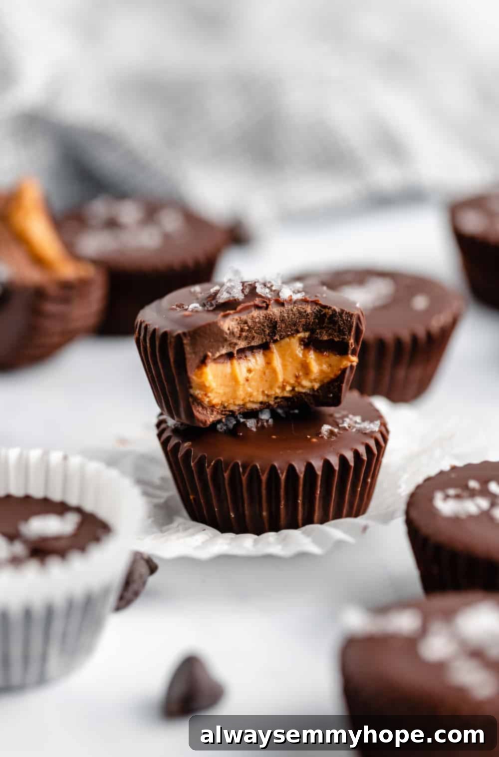 A stack of two perfectly set vegan peanut butter cups, with a light sprinkle of sea salt on top, showing off their rich chocolate exterior.