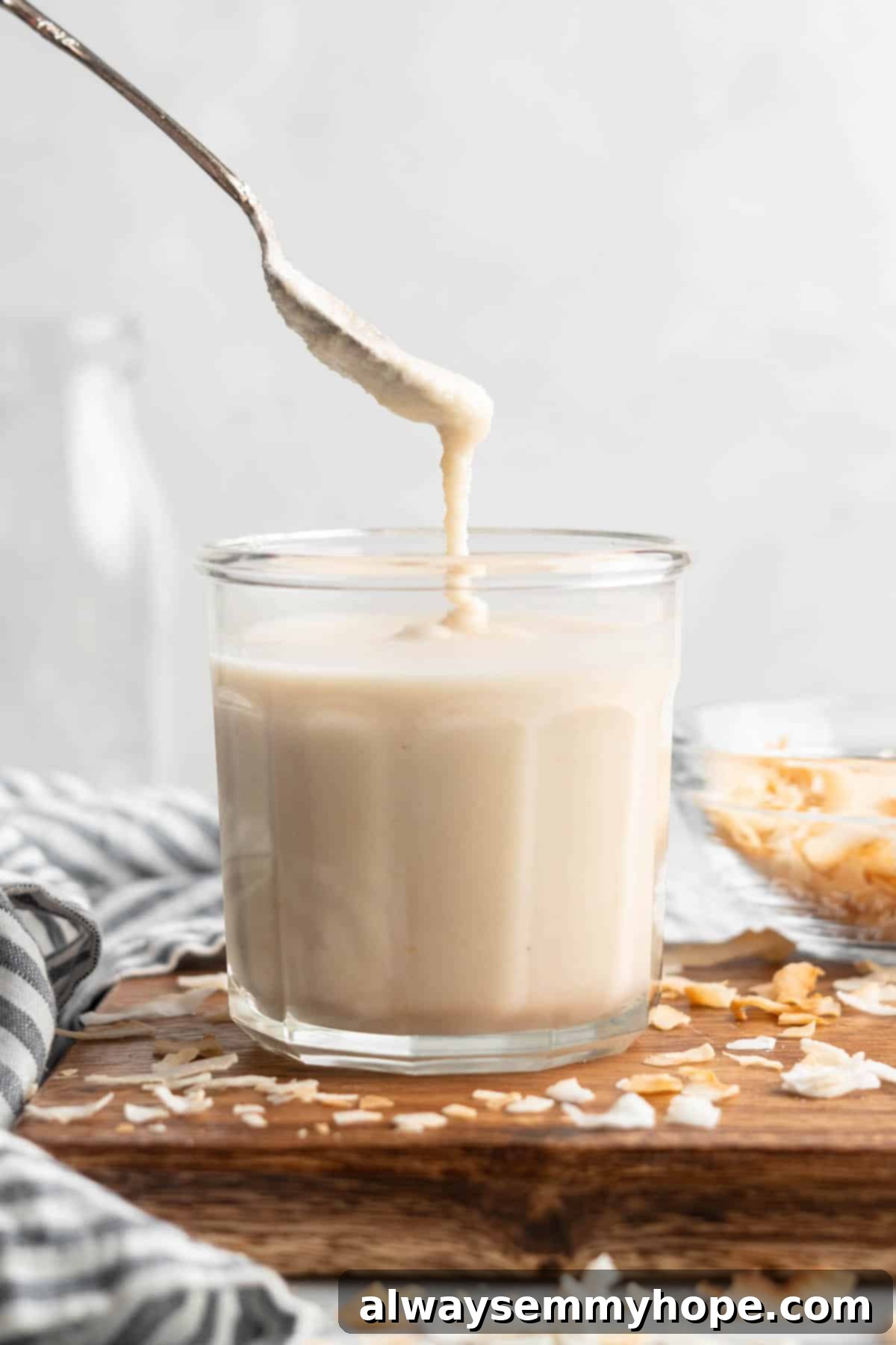 You won't believe how easy it is to make homemade coconut butter! All you need is a food processor, coconut flakes, and this simple tutorial. Spoon drizzling coconut butter into a jar.