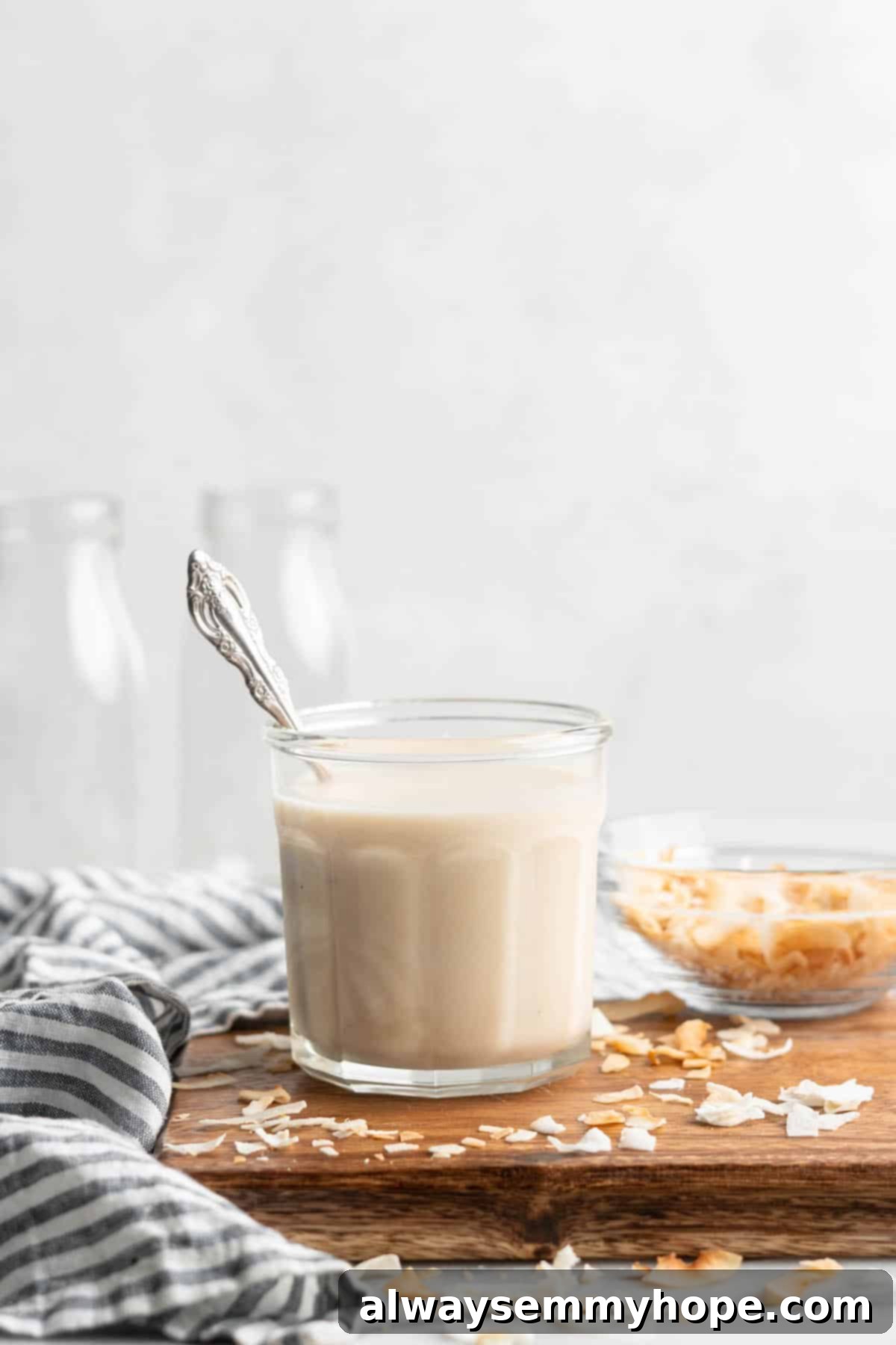 You won't believe how easy it is to make homemade coconut butter! All you need is a food processor, coconut flakes, and this simple tutorial. Jar of coconut butter with a spoon.