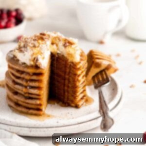 Stack of gingerbread pancakes topped with coconut whipped cream and maple syrup