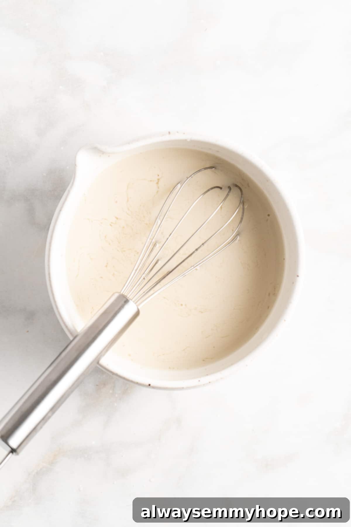 Whisking plant-based milk and apple cider vinegar together to create vegan buttermilk for gingerbread pancakes.