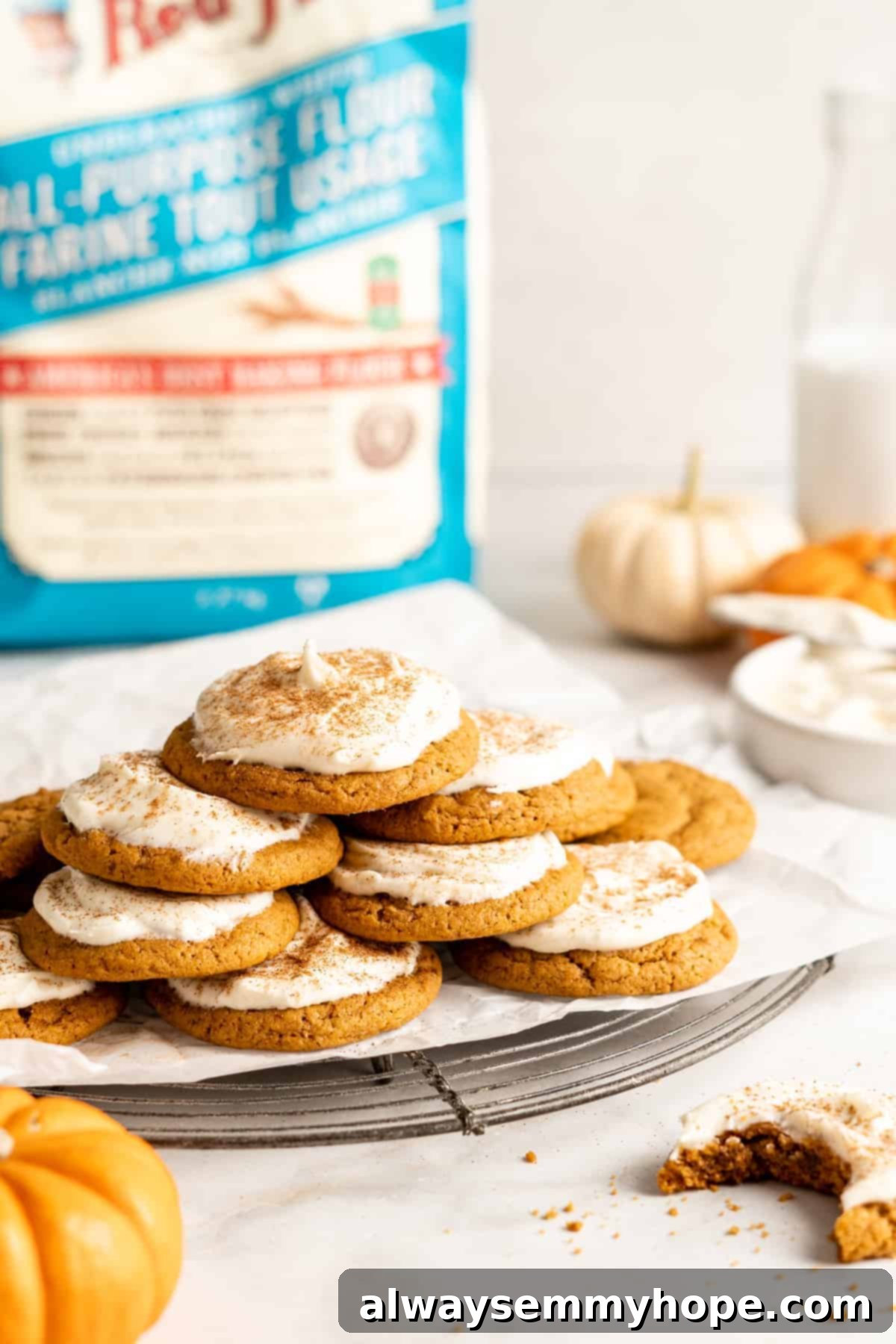 These easy vegan pumpkin cookies are ultra-soft. Made with 10 ingredients, they're topped with an irresistible cream cheese frosting, too! A stack of beautifully frosted vegan pumpkin cookies, adorned with cream cheese frosting and pumpkin spice, ready to be enjoyed.