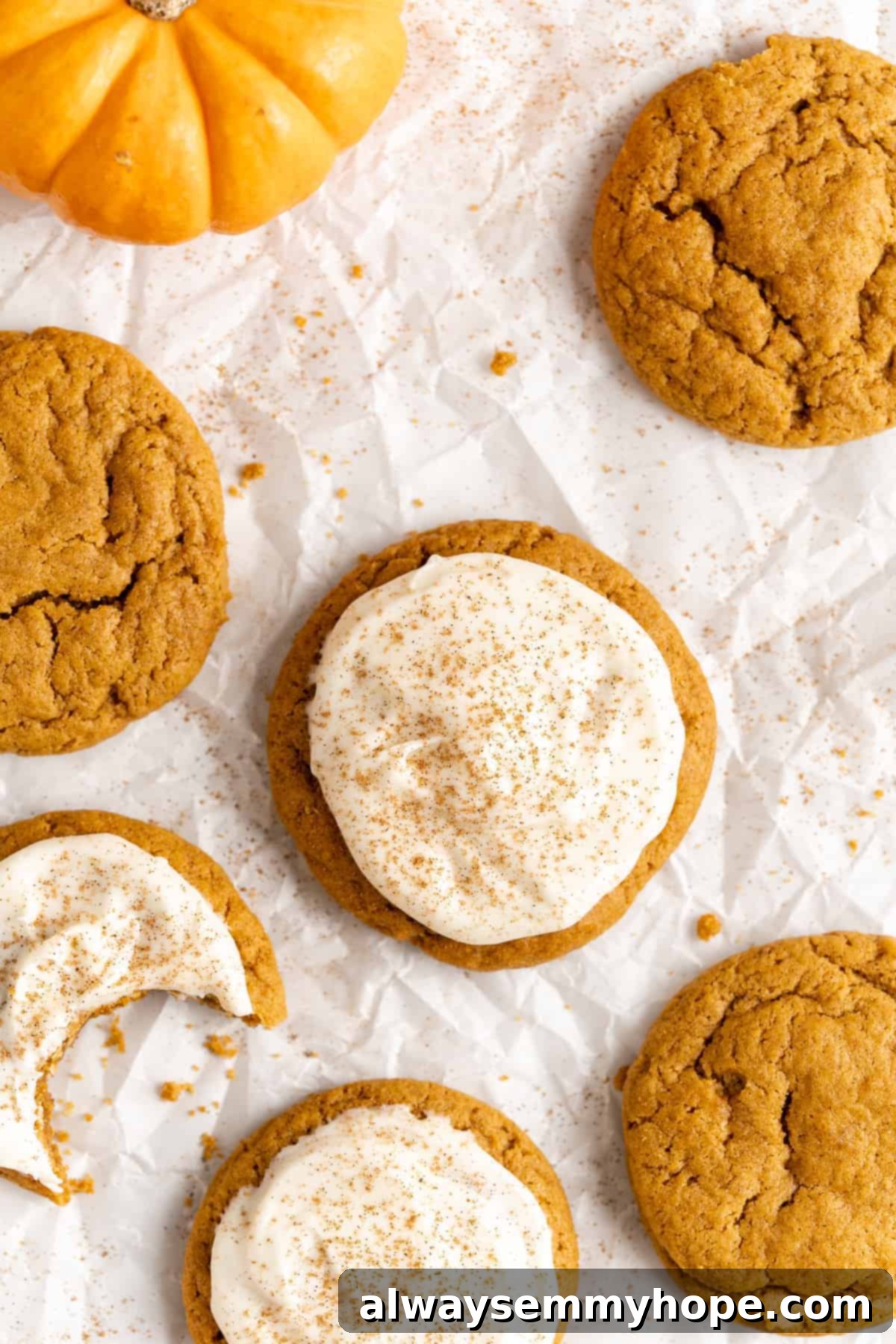 These easy vegan pumpkin cookies are ultra-soft. Made with 10 ingredients, they're topped with an irresistible cream cheese frosting, too! Close-up of perfectly baked and some frosted vegan pumpkin sugar cookies on parchment paper, highlighting their soft texture and spice topping.