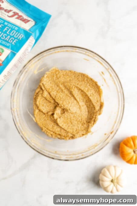 These easy vegan pumpkin cookies are ultra-soft. Made with 10 ingredients, they're topped with an irresistible cream cheese frosting, too! The cookie dough after pumpkin puree has been mixed in, displaying a rich orange hue and smooth consistency.