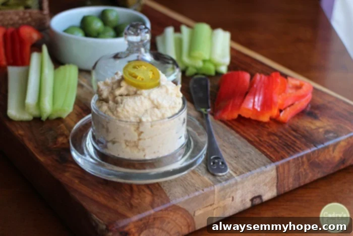 Vegan Christmas Delights: 50 Festive Plant-Based Meals 8 Jalapeno cashew spread in a glass jar on a charcuterie board with raw vegetables.