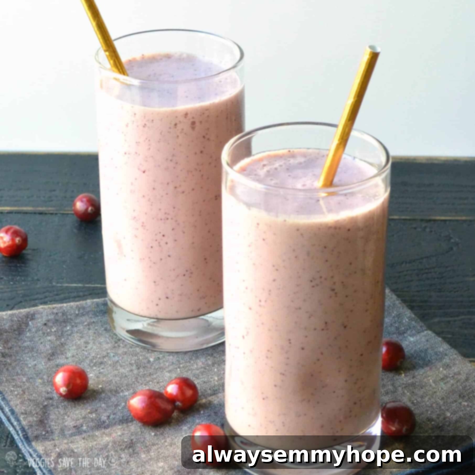 Vegan Christmas Delights: 50 Festive Plant-Based Meals 3 Two tall glasses of cranberry pistachio smoothie on a blue table.