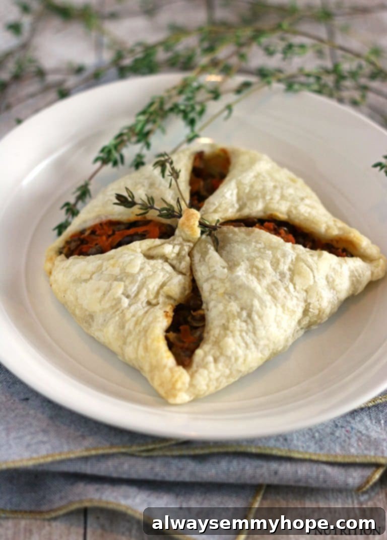 Vegan Christmas Delights: 50 Festive Plant-Based Meals 16 A lentil puff pastry pocket on a white plate with herb garnish.