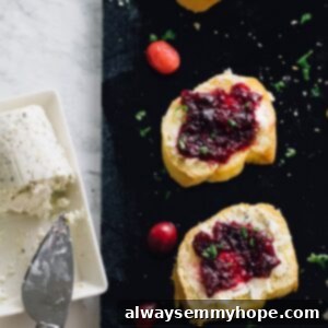 Top down shot of cranberry goat crostini on a black slate with cranberries.