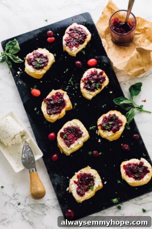 Overhead shot of crostini on a black slate, featuring fresh cranberries scattered around.