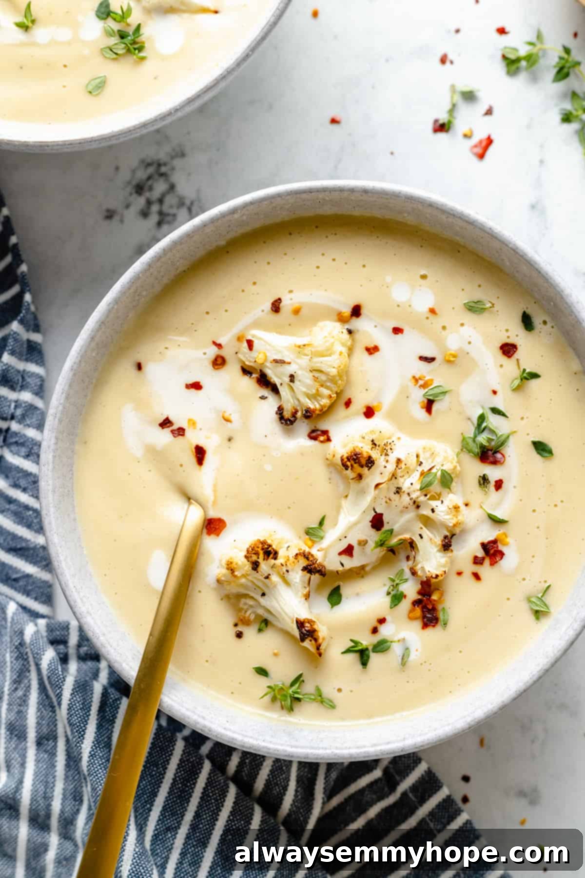 Velvety Roasted Cauliflower Soup 2 Overhead view of Roasted Cauliflower Soup garnished with cauliflower, red pepper flakes, and thyme