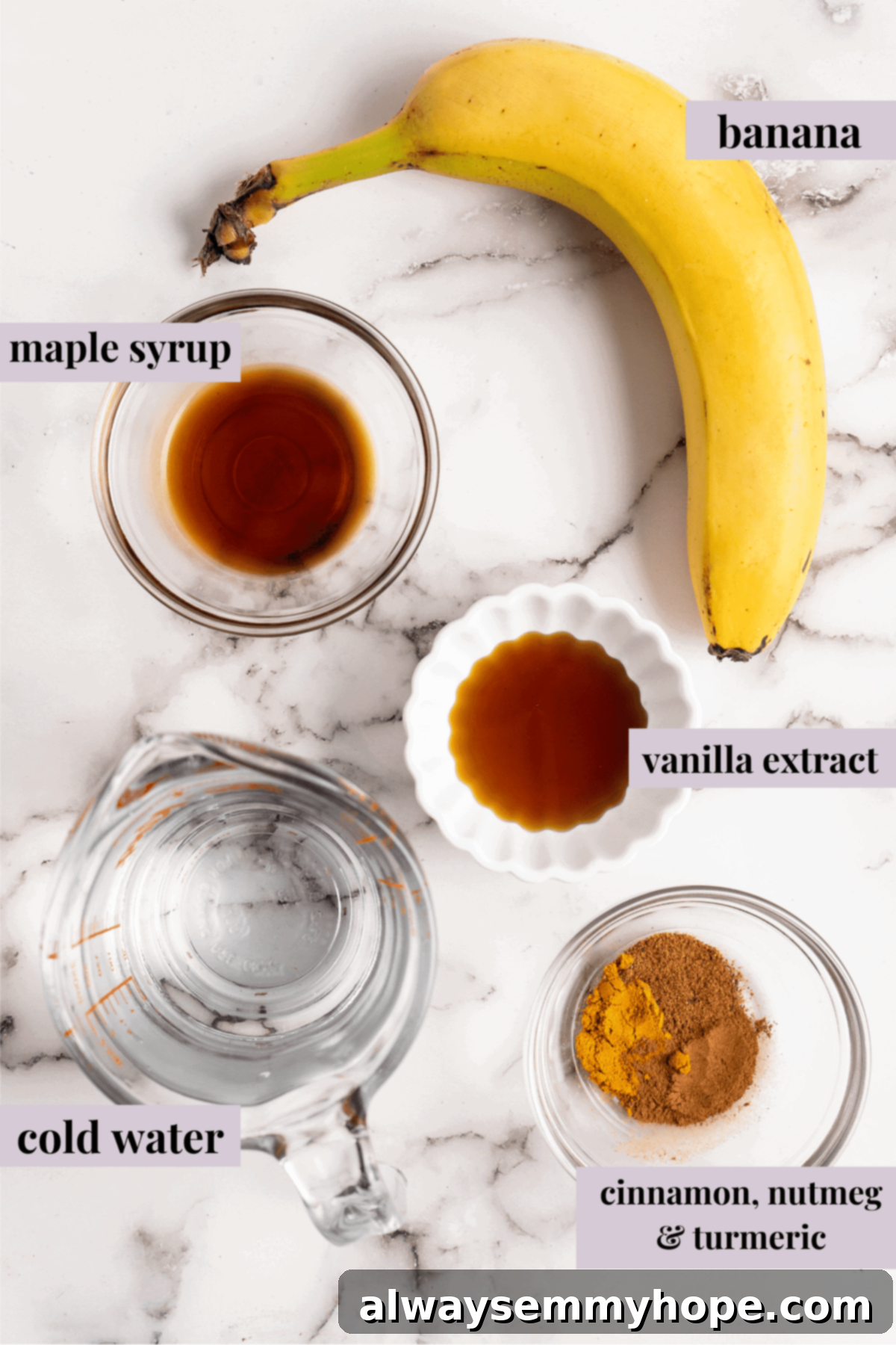 Overhead view of a peeled banana, a glass of water, and small bowls of optional spices like cinnamon and nutmeg, ready for making banana milk.