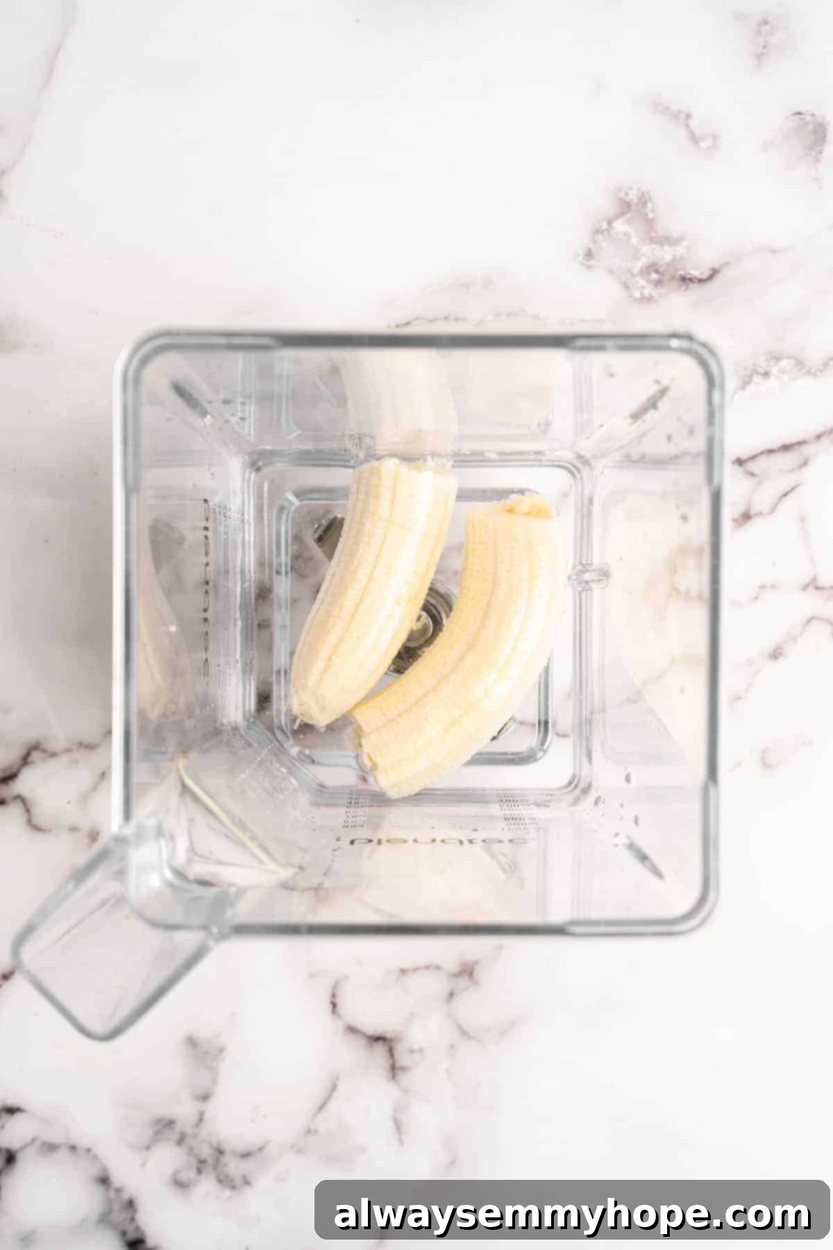 Two banana halves placed inside a high-speed blender, ready to be blended with water.