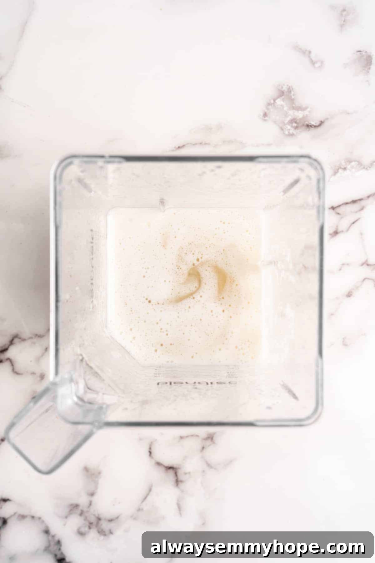 Overhead view of smooth banana milk swirling in a blender, indicating it's fully blended.