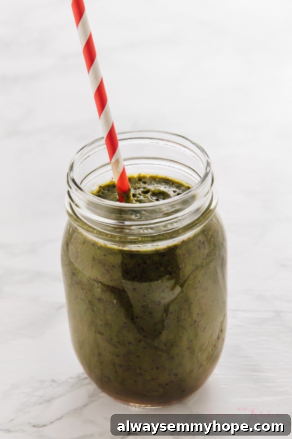 7 Simple and Speedy Vegan Banana Smoothies 11 A nutritious blueberry pineapple spinach smoothie in a glass mason jar with a red straw, showcasing its vibrant color.
