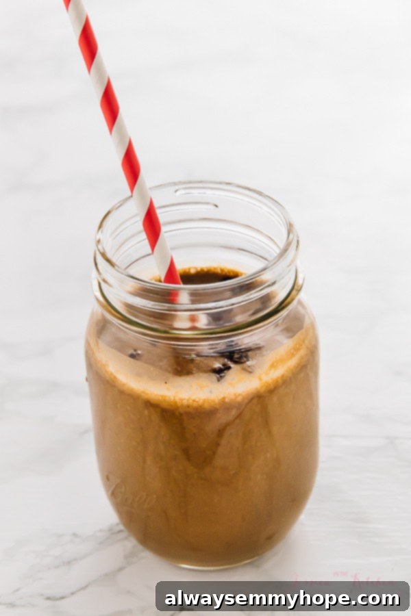 7 Simple and Speedy Vegan Banana Smoothies 14 A rich and indulgent chocolate peanut butter smoothie in a glass mason jar with a straw, promising a satisfying treat.