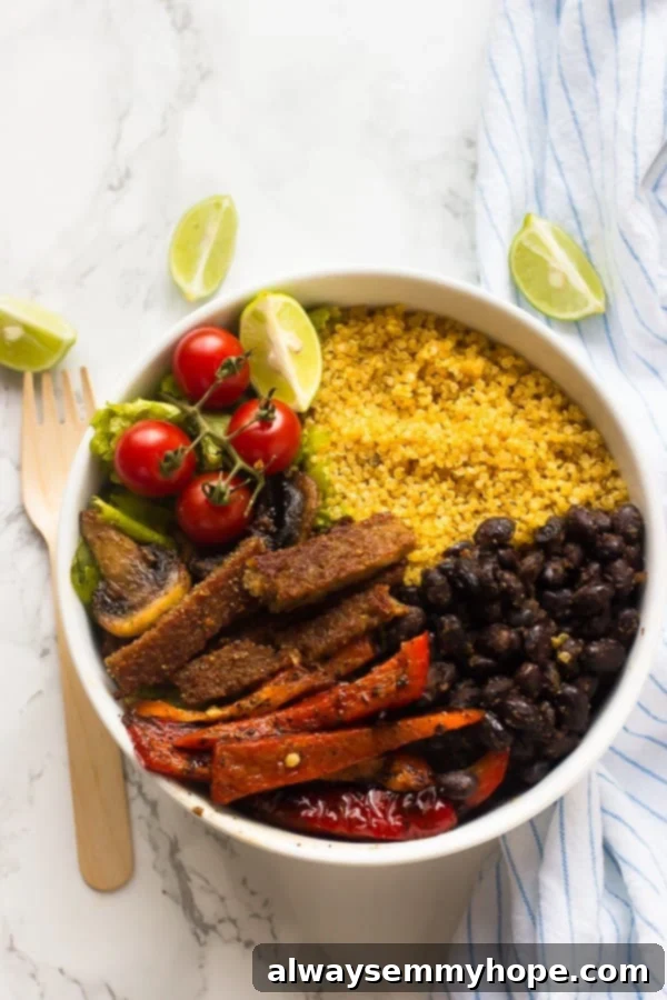 Top down shot of a fajita bowl with a wooden spoon on the side. 
