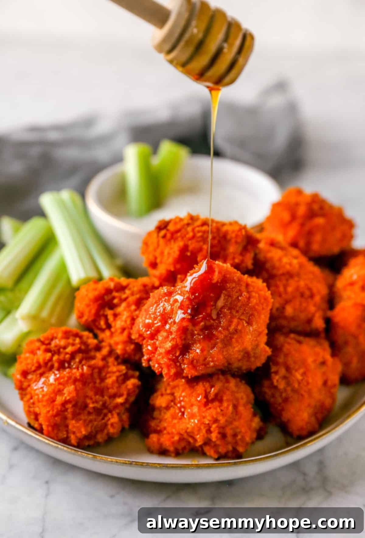 Buffalo cauliflower wings are the best vegan appetizer for game day! They're spicy and oven-baked to crispy perfection. Yum! A vibrant plate of buffalo cauliflower wings served with crisp celery sticks and a side of creamy ranch dip, perfect for sharing.