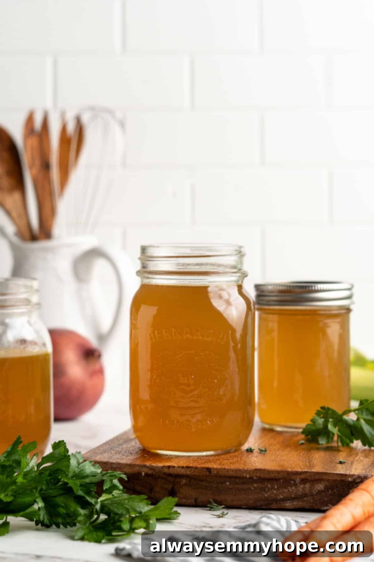 Learn how to make vegetable broth with veggie scraps. It’s the best broth you'll ever have, plus easy, cost-effective, and freezer-friendly! Three jars of homemade vegetable broth, surrounded by broth ingredients