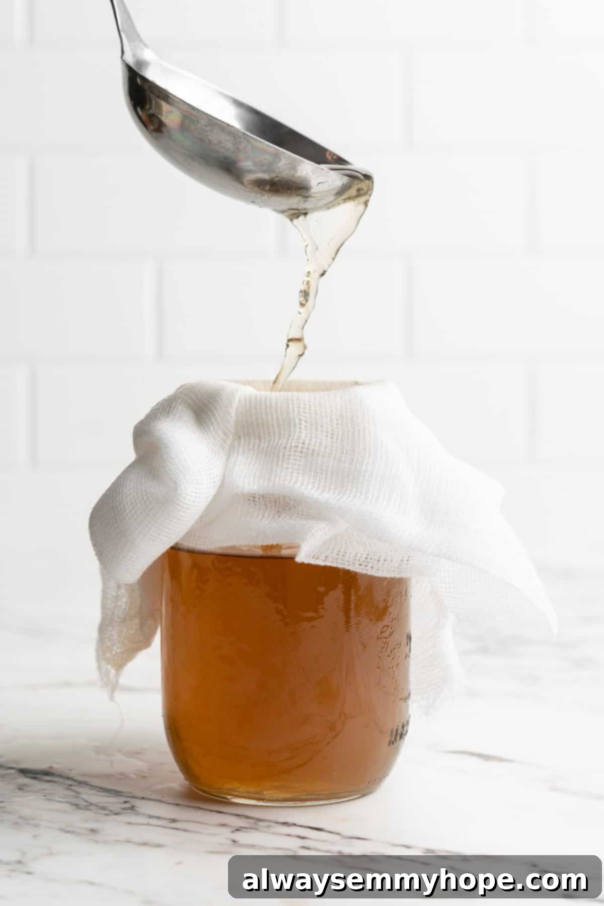 Learn how to make vegetable broth with veggie scraps. It’s the best broth you'll ever have, plus easy, cost-effective, and freezer-friendly! Ladling vegetable broth into jar topped with cheesecloth