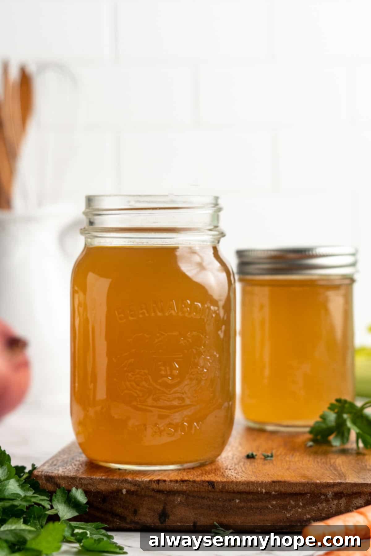 Learn how to make vegetable broth with veggie scraps. It’s the best broth you'll ever have, plus easy, cost-effective, and freezer-friendly! Two jars of homemade vegetable broth on wood cutting board